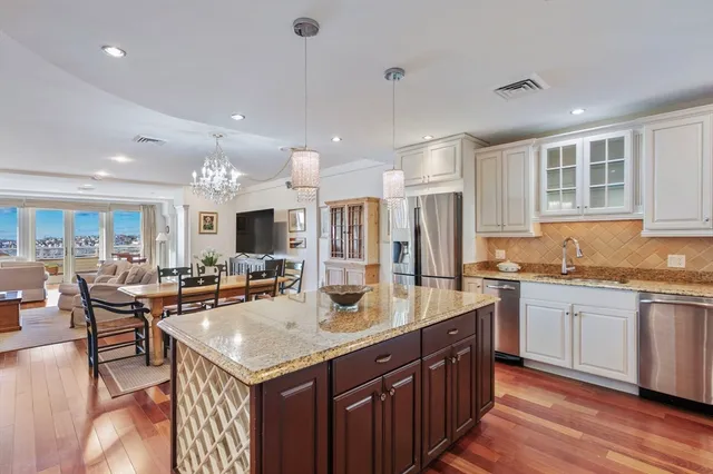 a open kitchen with stainless steel appliances granite countertop a sink stove and cabinets with wooden floor