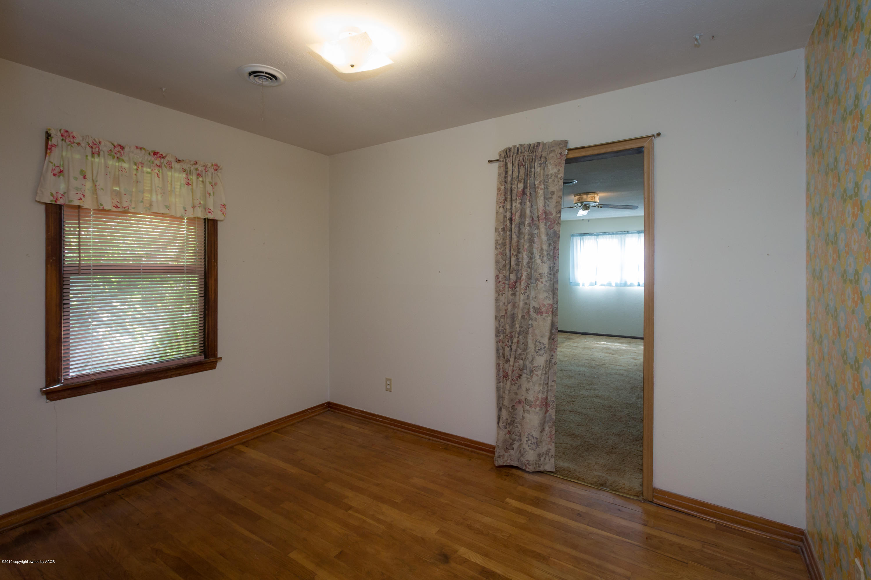 4606 Bowie Street Amarillo, TX 79110 - Photo 8 of 42 an empty room with wooden floor and a window