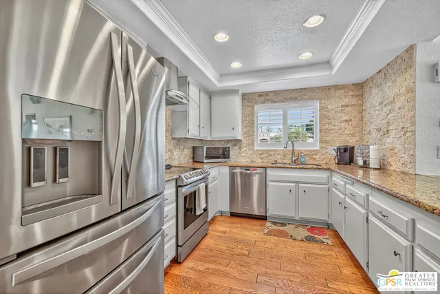 a large kitchen with stainless steel appliances granite countertop a stove a sink and a refrigerator