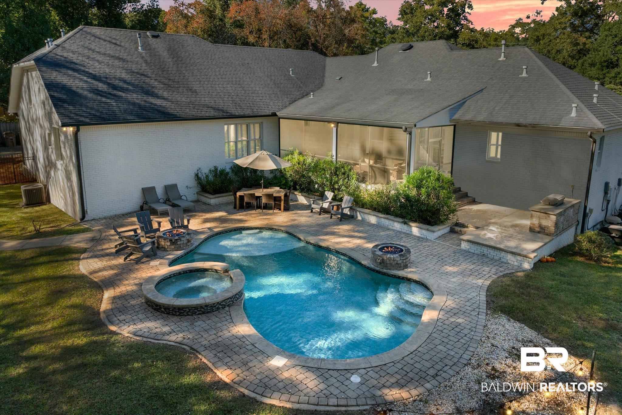 3713 Old Shell Road Mobile, AL 36608 - Photo 3 of 52 Pool at dusk with an in ground hot tub, exterior bar, an outdoor fire pit, a patio area, and a yard