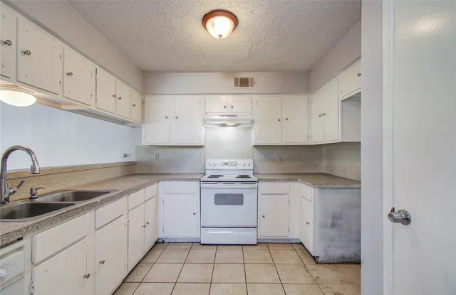 a kitchen with a stove sink and cabinets