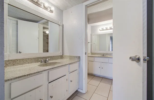 a bathroom with a granite countertop sink mirror and cabinets