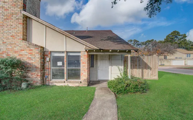 a view of a house with brick walls and a yard with plants