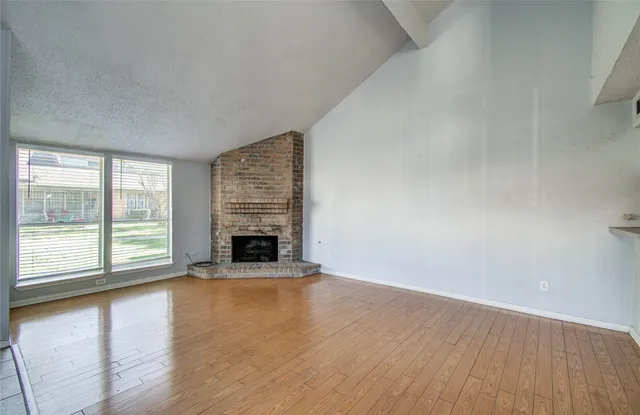 wooden floor fireplace and windows in an empty room