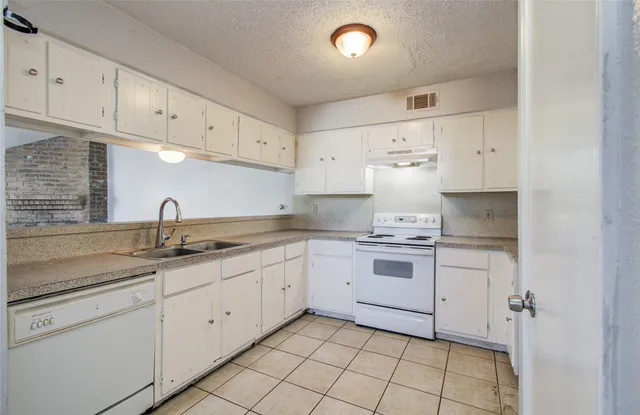 a kitchen with kitchen island granite countertop white cabinets white stainless steel appliances with a sink and dishwasher