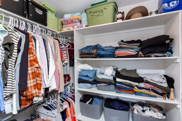a view of walk in closet with clothes and shoes
