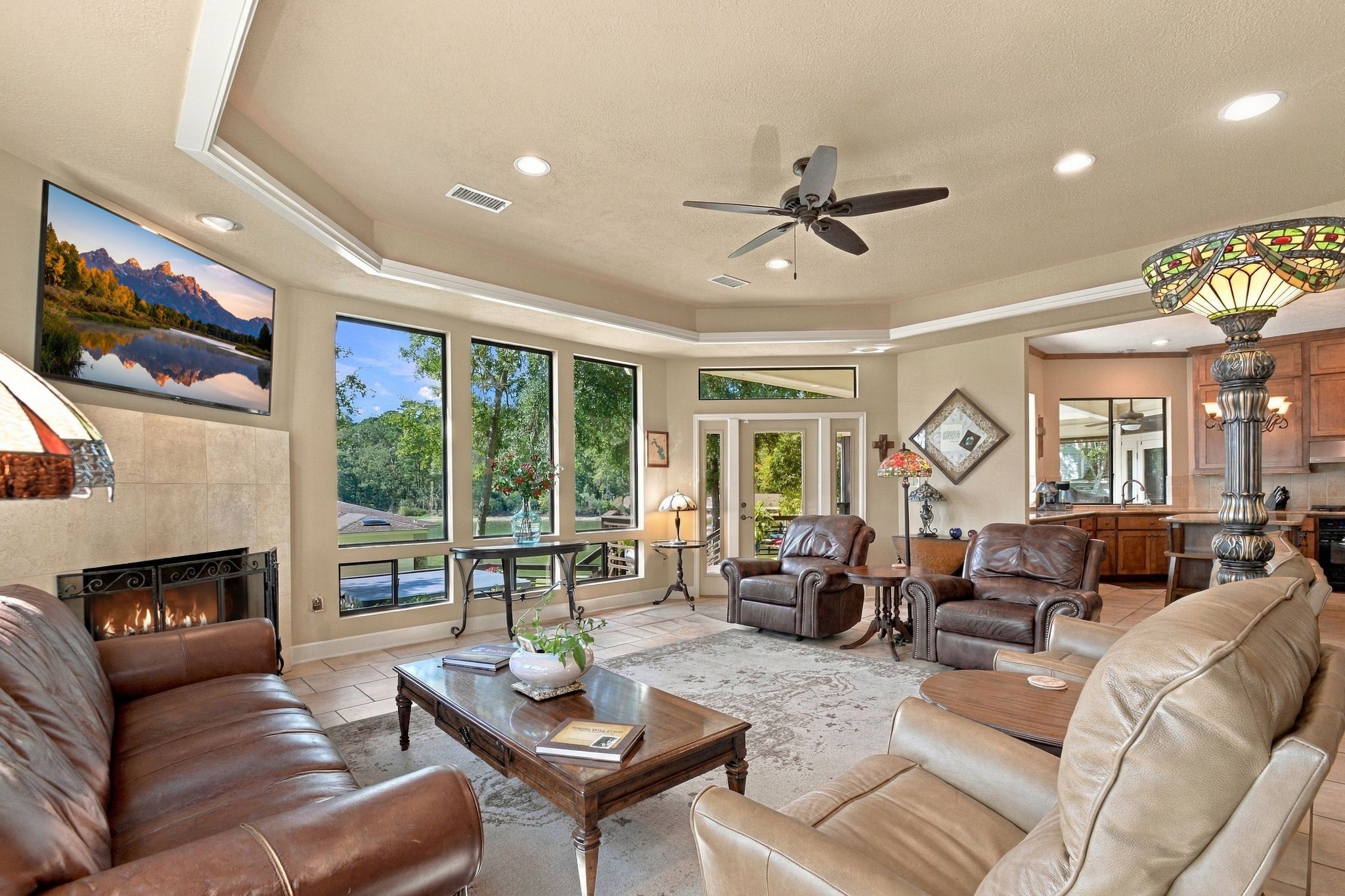 20341 Bay Hill Road Point Blank, TX 77364 - Photo 4 of 50 Large and wide-open windows with Million-Dollar views, a cozy fireplace, and elegant tray ceiling, seamlessly connecting to the open kitchen for an inviting atmosphere.