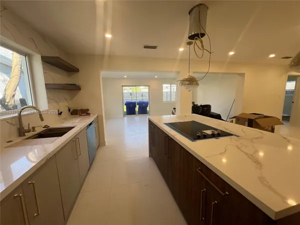 a large kitchen with a large counter top a sink a window and stainless steel appliances
