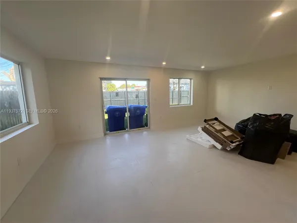 an empty room with windows and ceiling fan