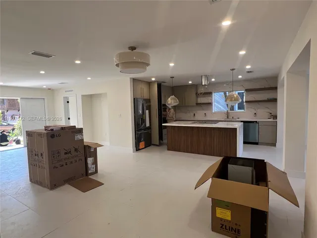 a large kitchen with stainless steel appliances kitchen island granite countertop a refrigerator and a stove top oven with wooden floor