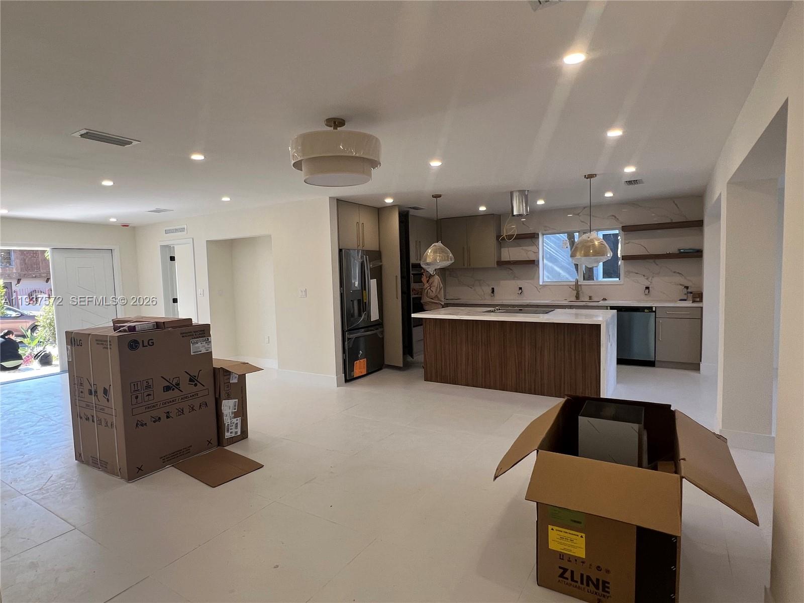 2315 Northwest 3rd Street Miami, FL 33125 - Photo 2 of 15 a large kitchen with stainless steel appliances kitchen island granite countertop a refrigerator and a stove top oven with wooden floor