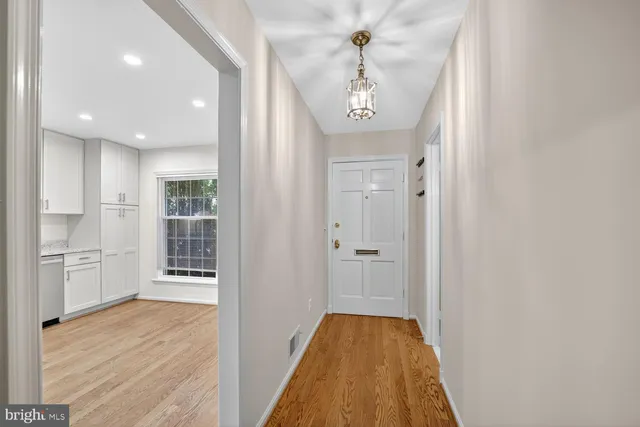 a view of a hallway with wooden floor and a kitchen