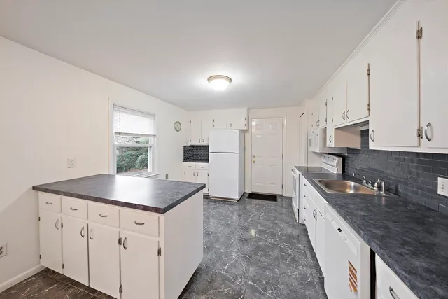 a kitchen with stainless steel appliances granite countertop a sink dishwasher and white cabinets with wooden floor
