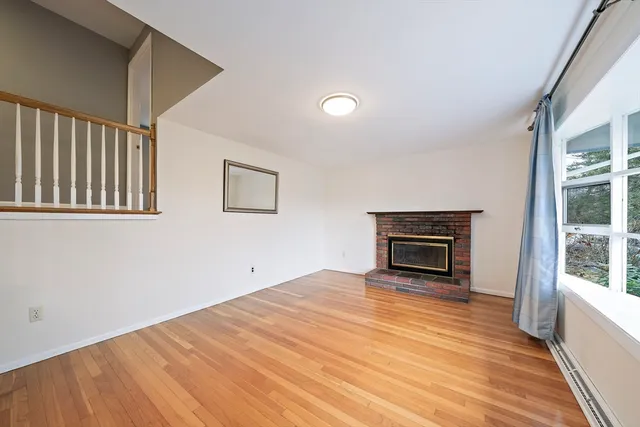 a view of empty room with wooden floor and fireplace