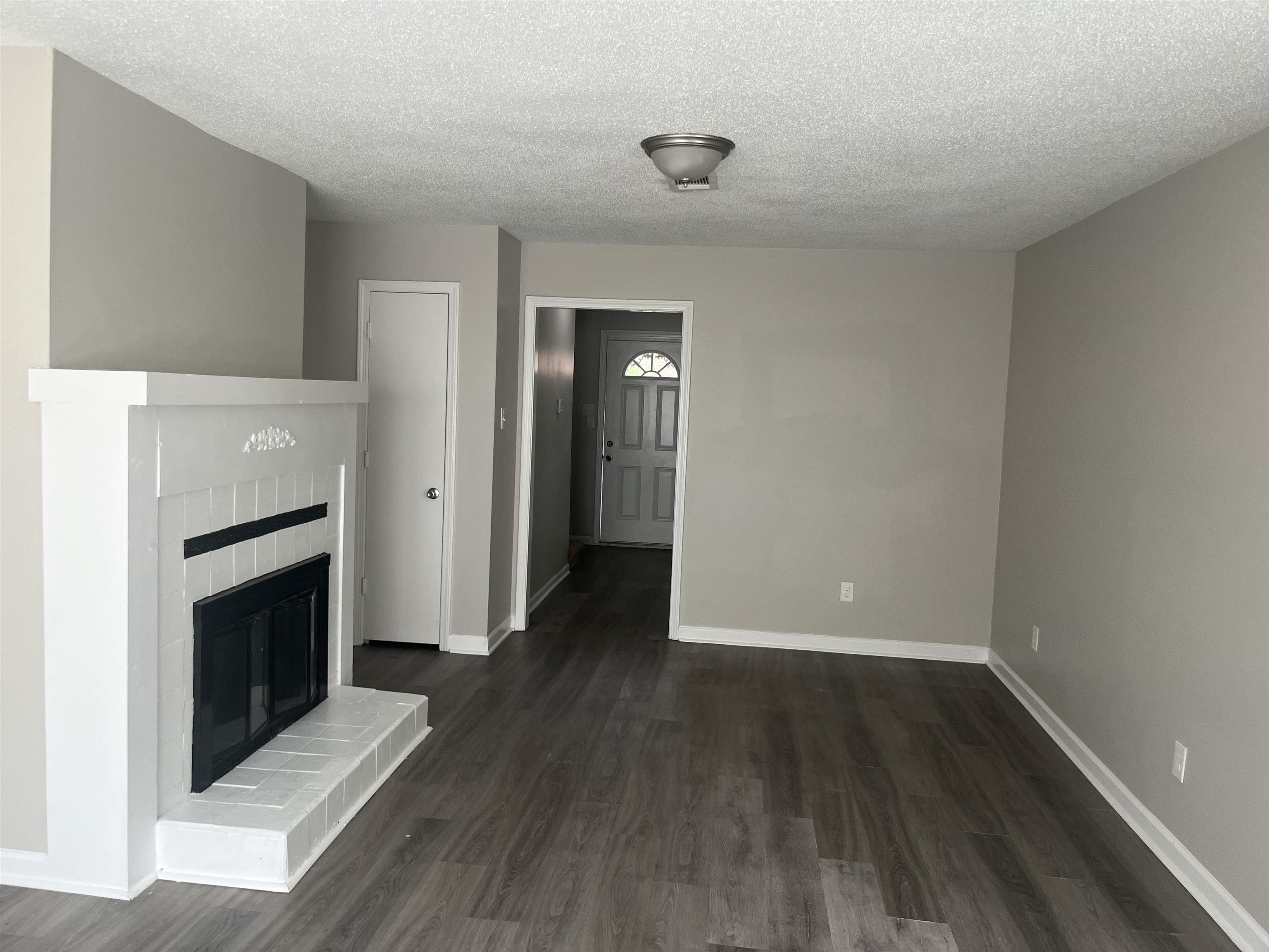 5994 Lofty Oak Road, Unit 5994 Memphis, TN 38115 - Photo 2 of 3 Unfurnished living room with a glass covered fireplace, dark wood-style floors, and a textured ceiling