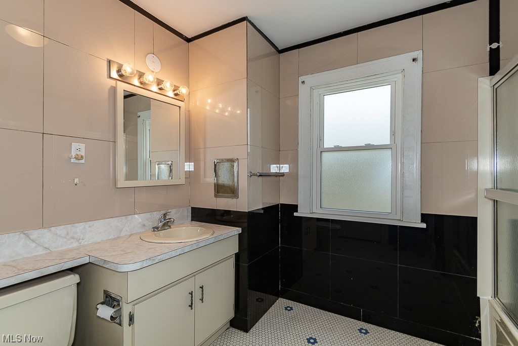29396 Detroit Road Westlake, OH 44145 - Photo 26 of 30 Bathroom featuring toilet, vanity with extensive cabinet space, and tile walls
