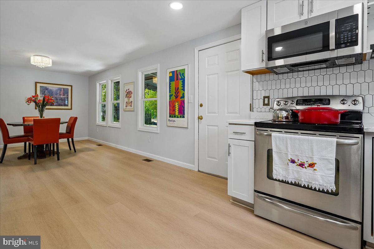 523 Widewater Road Stafford, VA 22554 - Photo 19 of 57 a open kitchen with stainless steel appliances kitchen island granite countertop a refrigerator a stove top oven a dining table and chairs with wooden floor