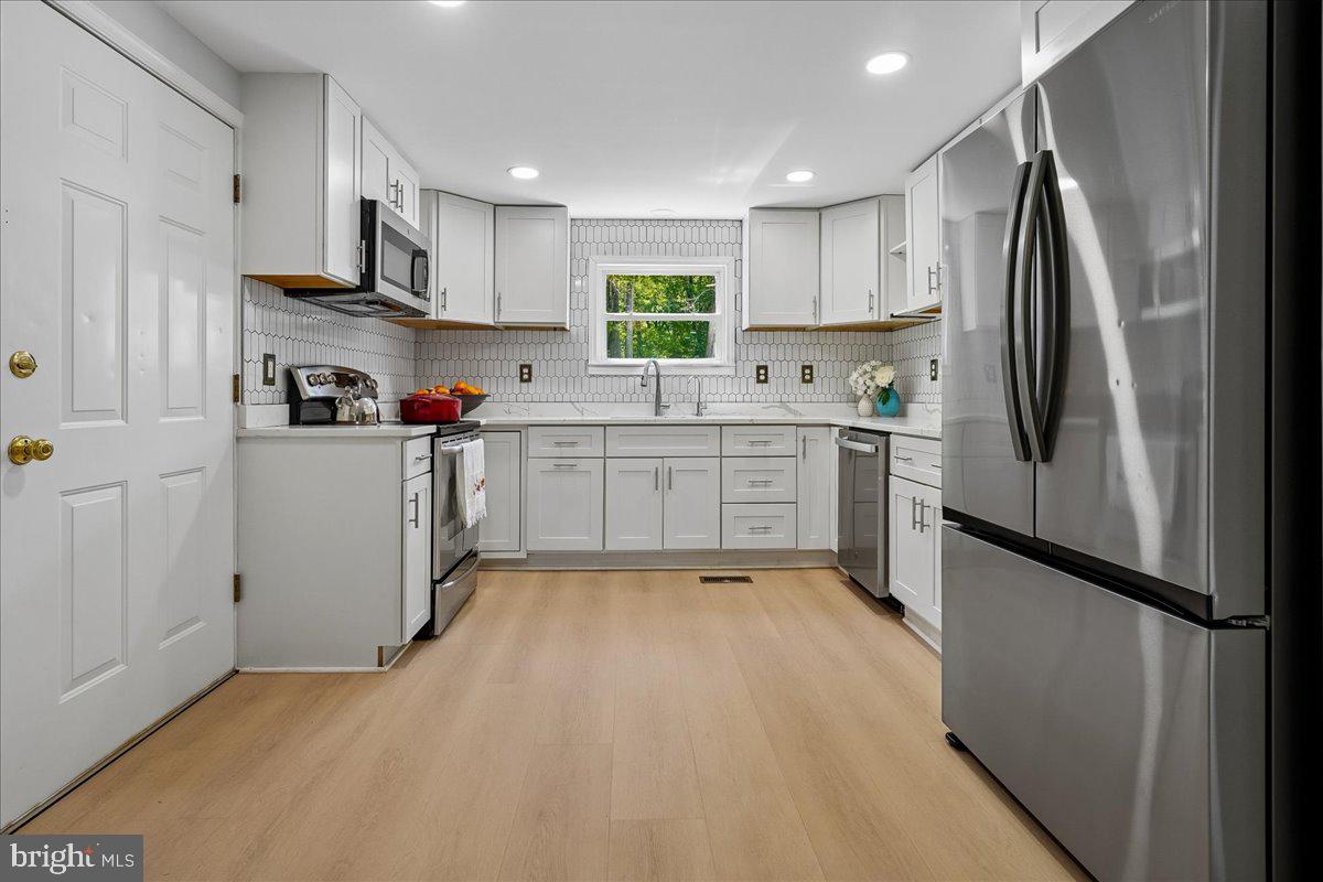 523 Widewater Road Stafford, VA 22554 - Photo 21 of 57 a kitchen with stainless steel appliances granite countertop a refrigerator a sink dishwasher a stove and white cabinets with wooden floor