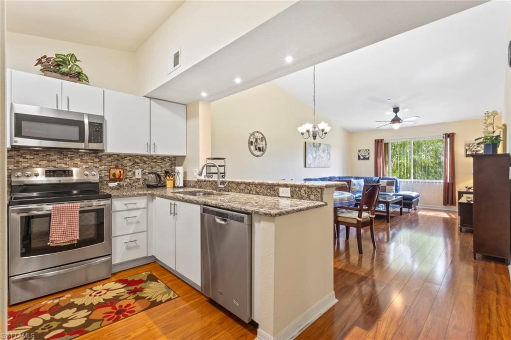 8288 Key Royal Lane, Unit 1435 Naples, FL 34119 - Photo 7 of 26 a kitchen with granite countertop a stove a sink a dining table and chairs with wooden floor
