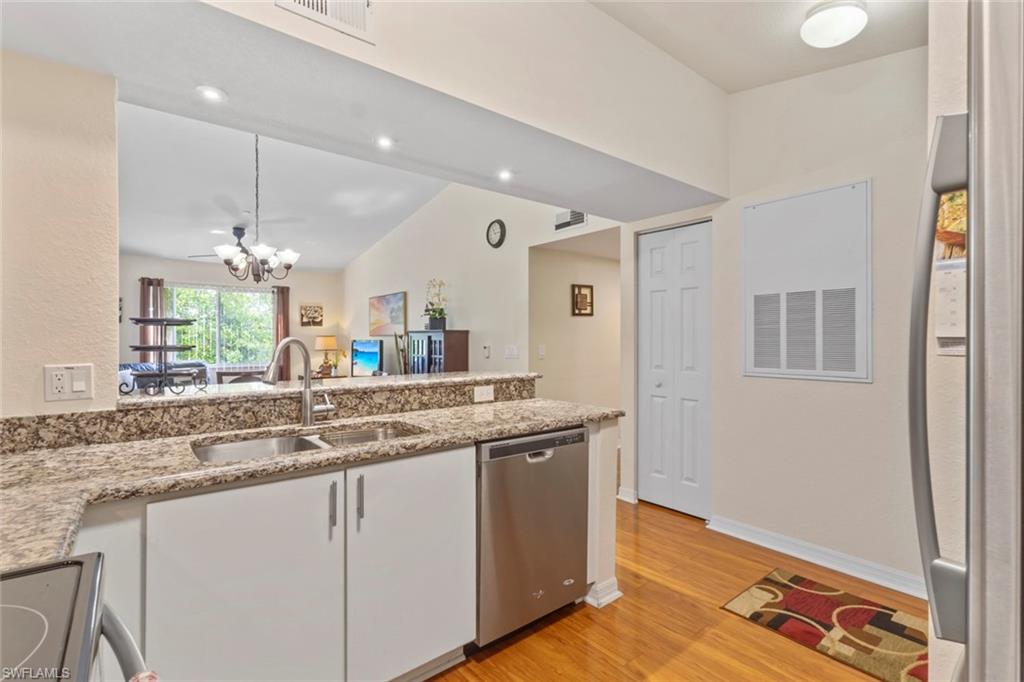8288 Key Royal Lane, Unit 1435 Naples, FL 34119 - Photo 9 of 26 a kitchen with stainless steel appliances granite countertop a sink and a wooden floor