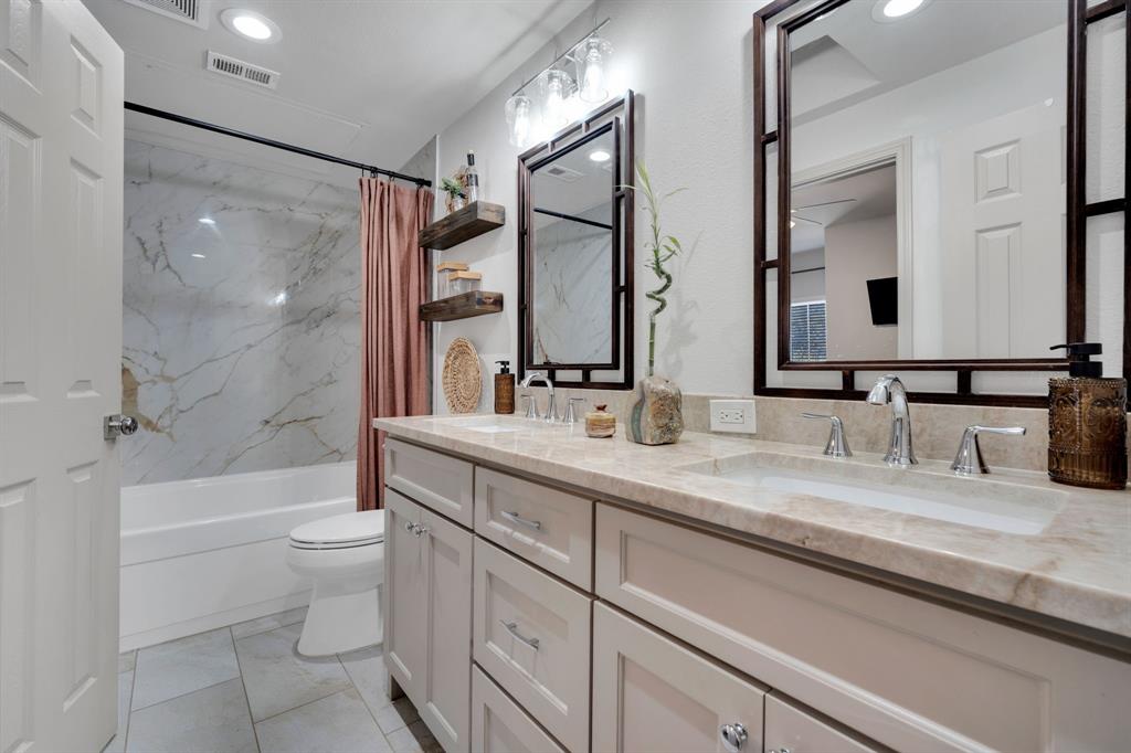 a bathroom with a double vanity sink toilet mirror and bathtub