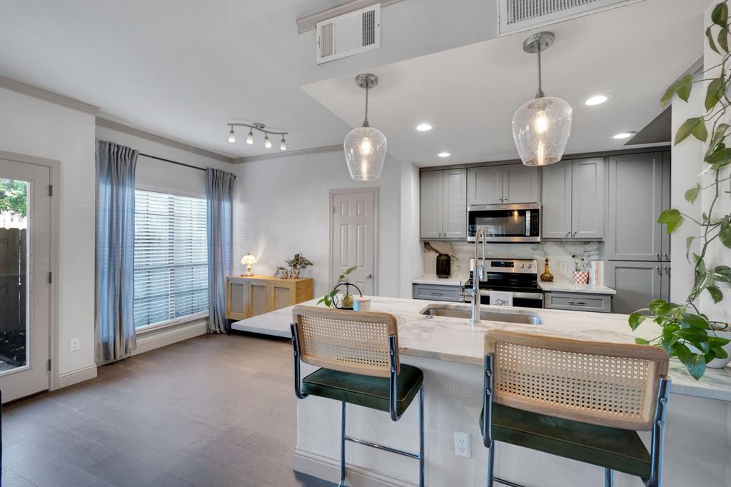 5619 Preston Oaks Road, Unit 802 Dallas, TX 75254 - Photo 2 of 27 a kitchen with stainless steel appliances kitchen island granite countertop a stove a sink dishwasher a dining table and chairs with wooden floor
