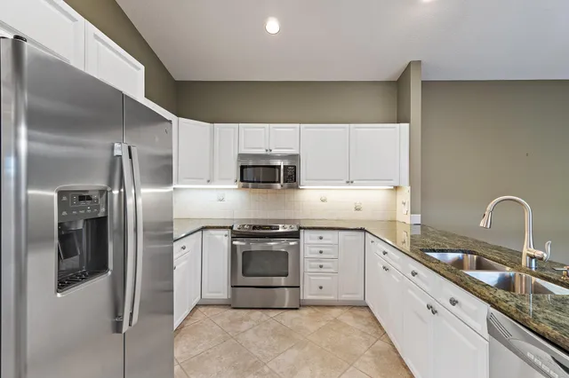 a kitchen with stainless steel appliances granite countertop a sink a stove a refrigerator and cabinets