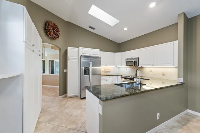 a kitchen with stainless steel appliances granite countertop a sink refrigerator and cabinets