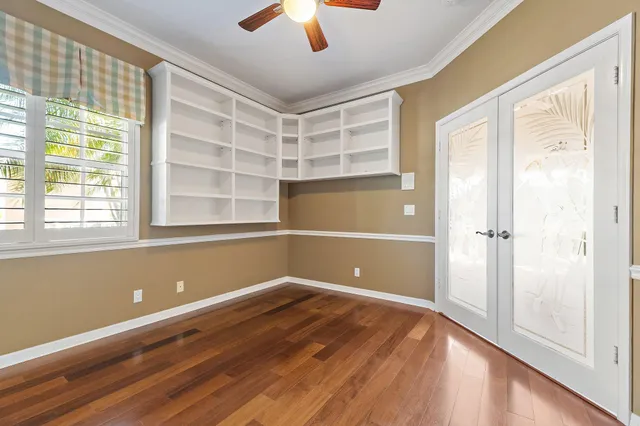 a view of empty room with wooden floor and fan