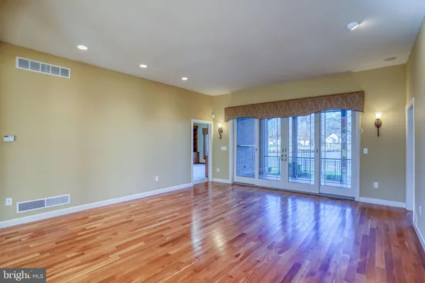 a view of a room with wooden floor chandelier and windows