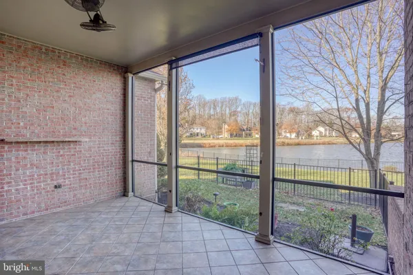 a view of an empty room with chandelier fan and kitchen view