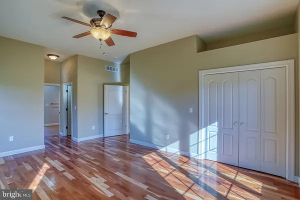 a view of empty room with wooden floor and fan