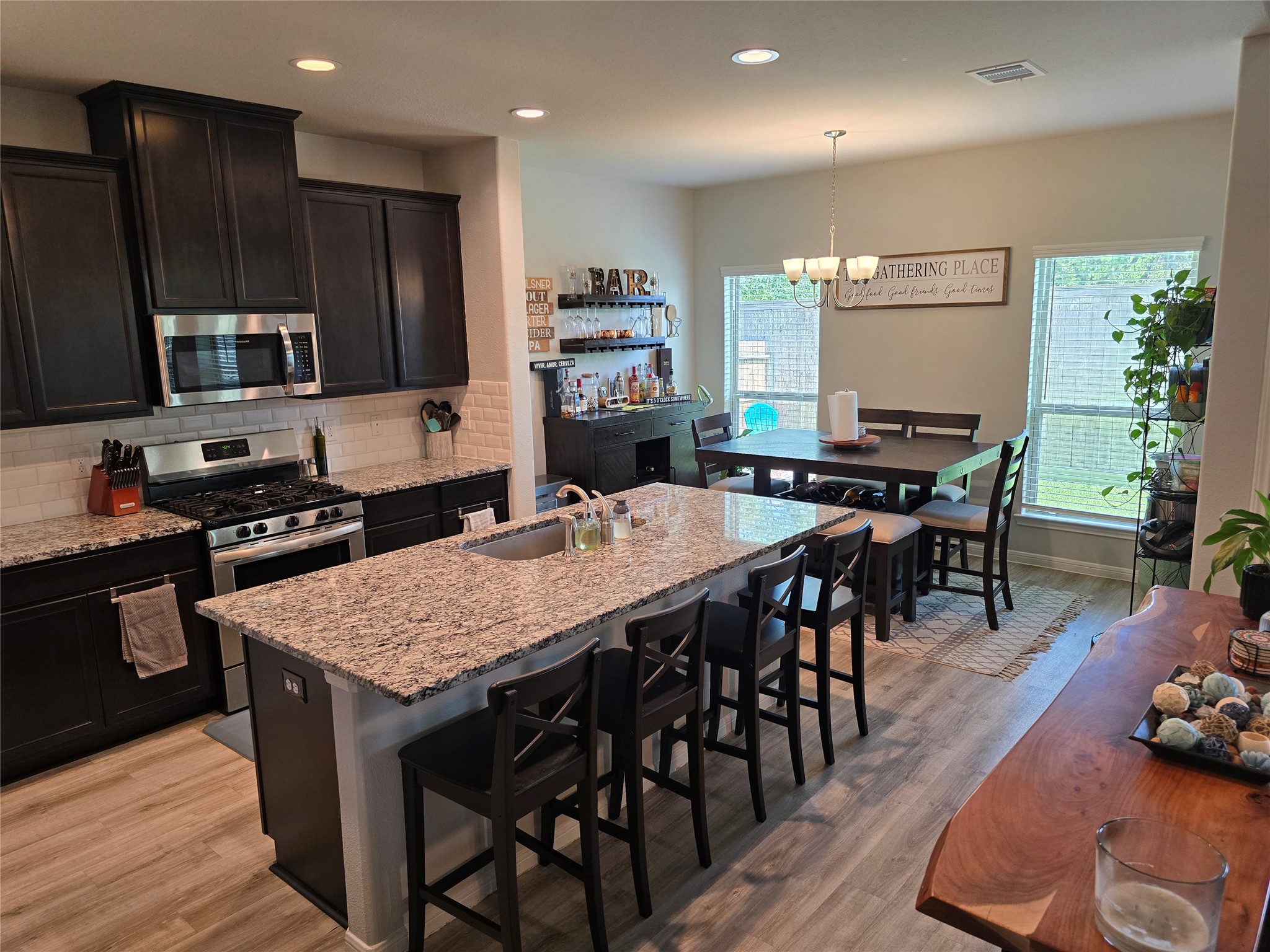 1942 Bending Green Drive Rosharon, TX 77583 - Photo 12 of 30 This modern kitchen features dark cabinets, stainless steel appliances, and a spacious granite island with seating. It's open to a dining area with large windows, offering plenty of natural light.