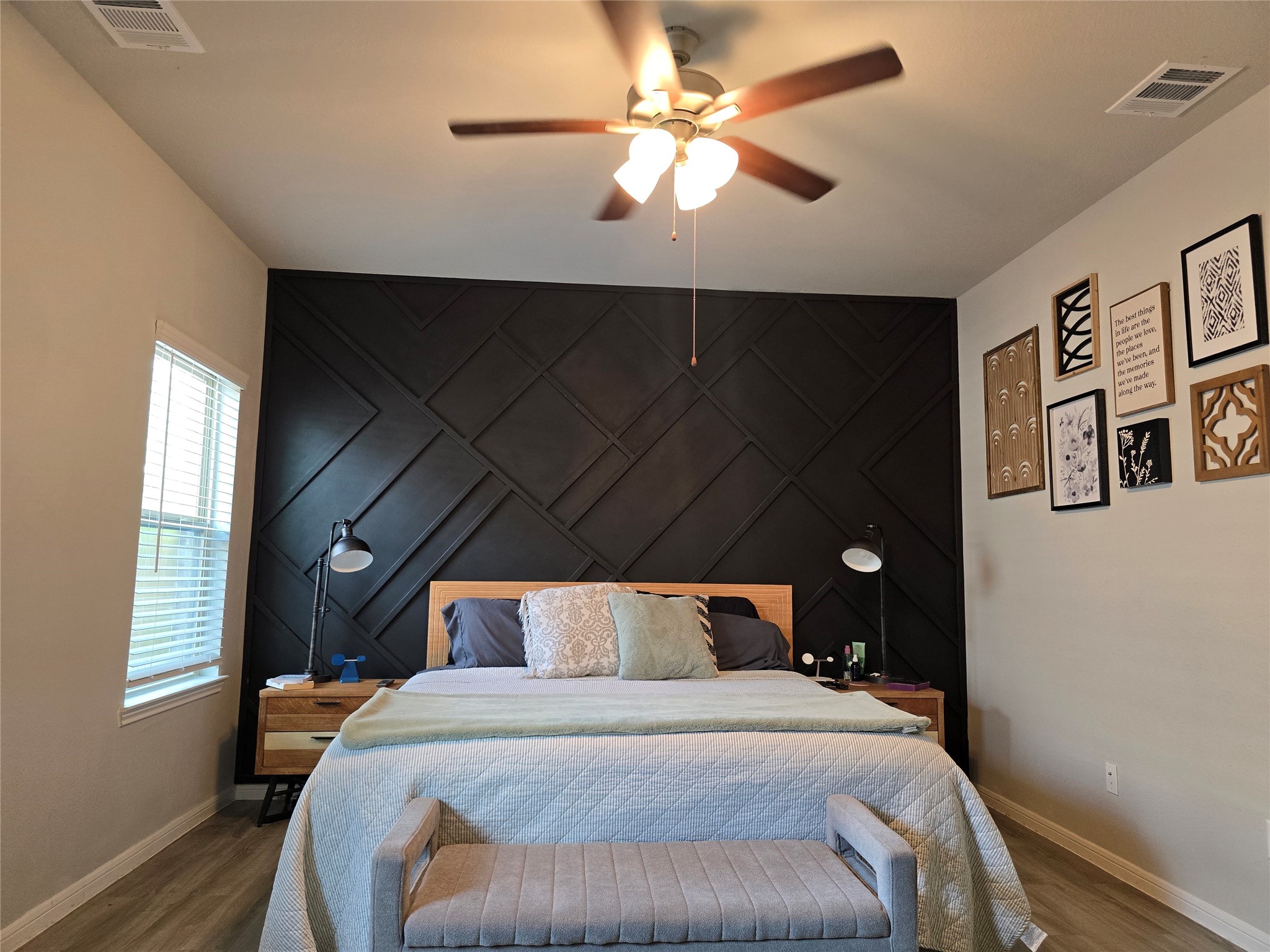 1942 Bending Green Drive Rosharon, TX 77583 - Photo 18 of 30 This bedroom features a chic black accent wall with a geometric pattern, complemented by modern furnishings. A ceiling fan provides comfort, while natural light streams through a window. Wall art adds a personal touch, creating a cozy and stylish retreat.
