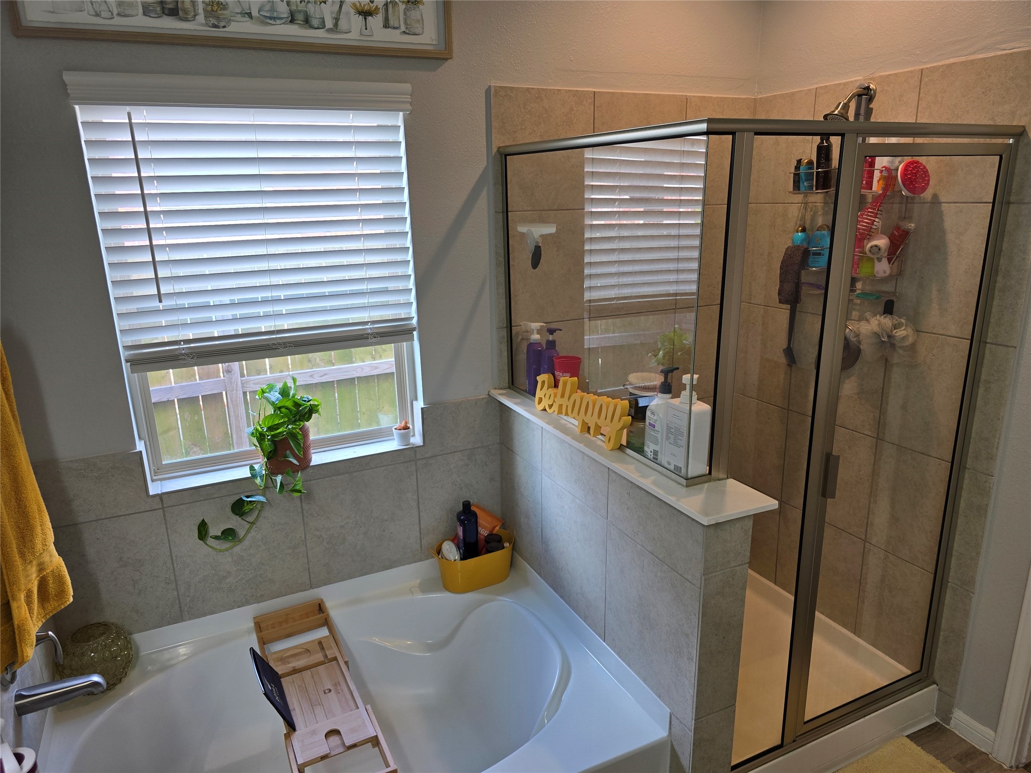 1942 Bending Green Drive Rosharon, TX 77583 - Photo 20 of 30 This inviting bathroom features a spacious soaking tub next to a window with blinds, providing natural light. Adjacent is a modern glass-enclosed shower with tile walls, offering a sleek and functional design.