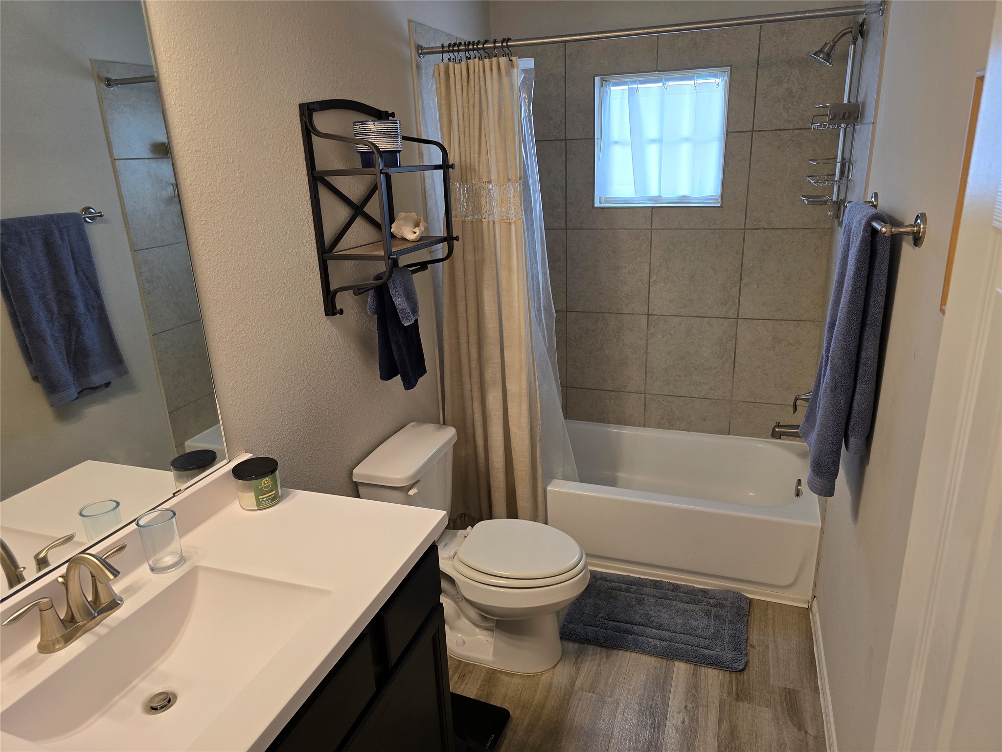 1942 Bending Green Drive Rosharon, TX 77583 - Photo 25 of 30 This bathroom features a modern design with a tiled shower and bathtub, a sleek white vanity with a large mirror, and neutral tones. It's well-lit with natural light from a small window, creating a clean and inviting space.