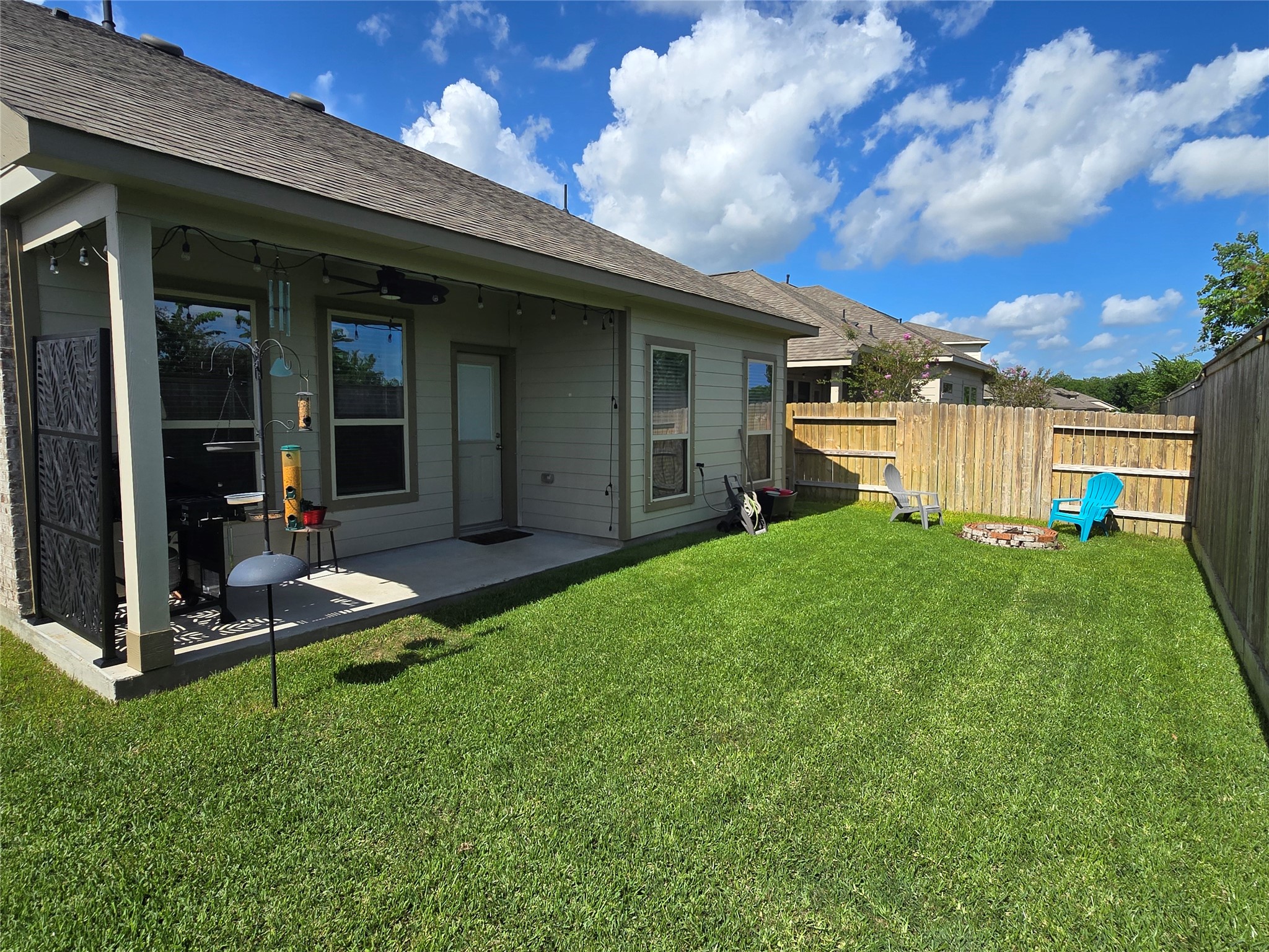 1942 Bending Green Drive Rosharon, TX 77583 - Photo 30 of 30 Spacious backyard with well-maintained lawn, covered patio, and a cozy fire pit area. Ideal for outdoor gatherings and relaxation.