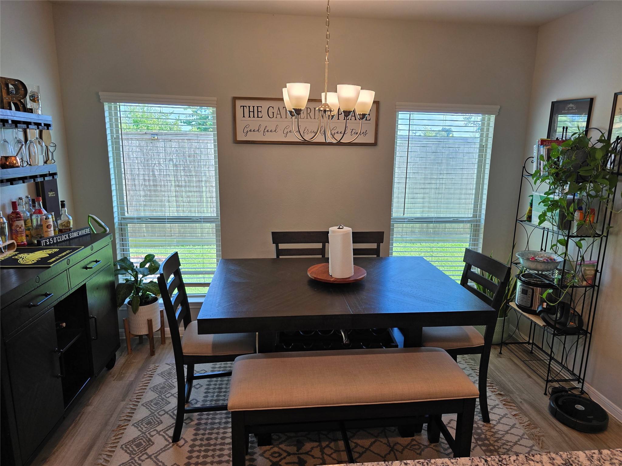 1942 Bending Green Drive Rosharon, TX 77583 - Photo 10 of 30 This dining area features a cozy, modern setup with a dark wood table, bench seating, and chairs. It’s well-lit by a stylish chandelier and natural light from two large windows. The space includes a bar area and a plant shelf, offering a welcoming atmosphere for gatherings.