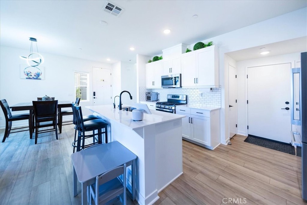 35246 Blossom Place Fallbrook, CA 92028 - Photo 15 of 62 a kitchen with stainless steel appliances a white table chairs and a wooden floor