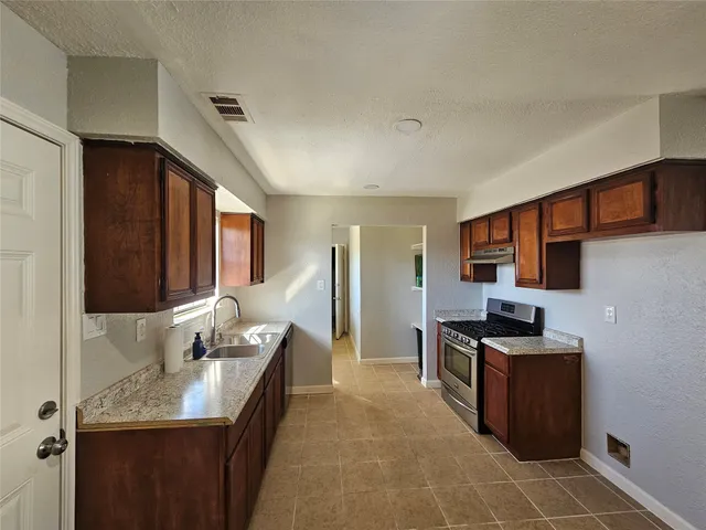 a kitchen with granite countertop a sink and a stove top oven