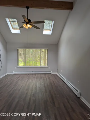 an empty room with wooden floor chandelier fan and windows