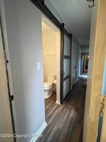 a view of a hallway with wooden floor and a living room