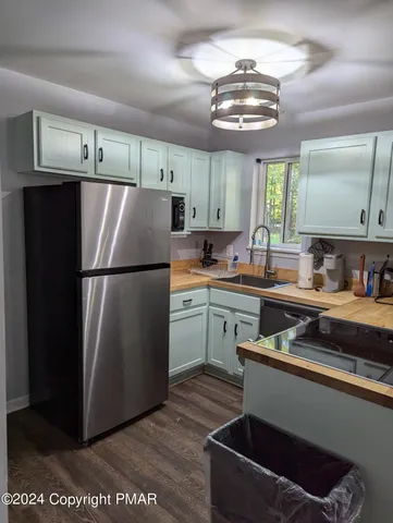 a kitchen with stainless steel appliances granite countertop a refrigerator a sink dishwasher a stove and white cabinets