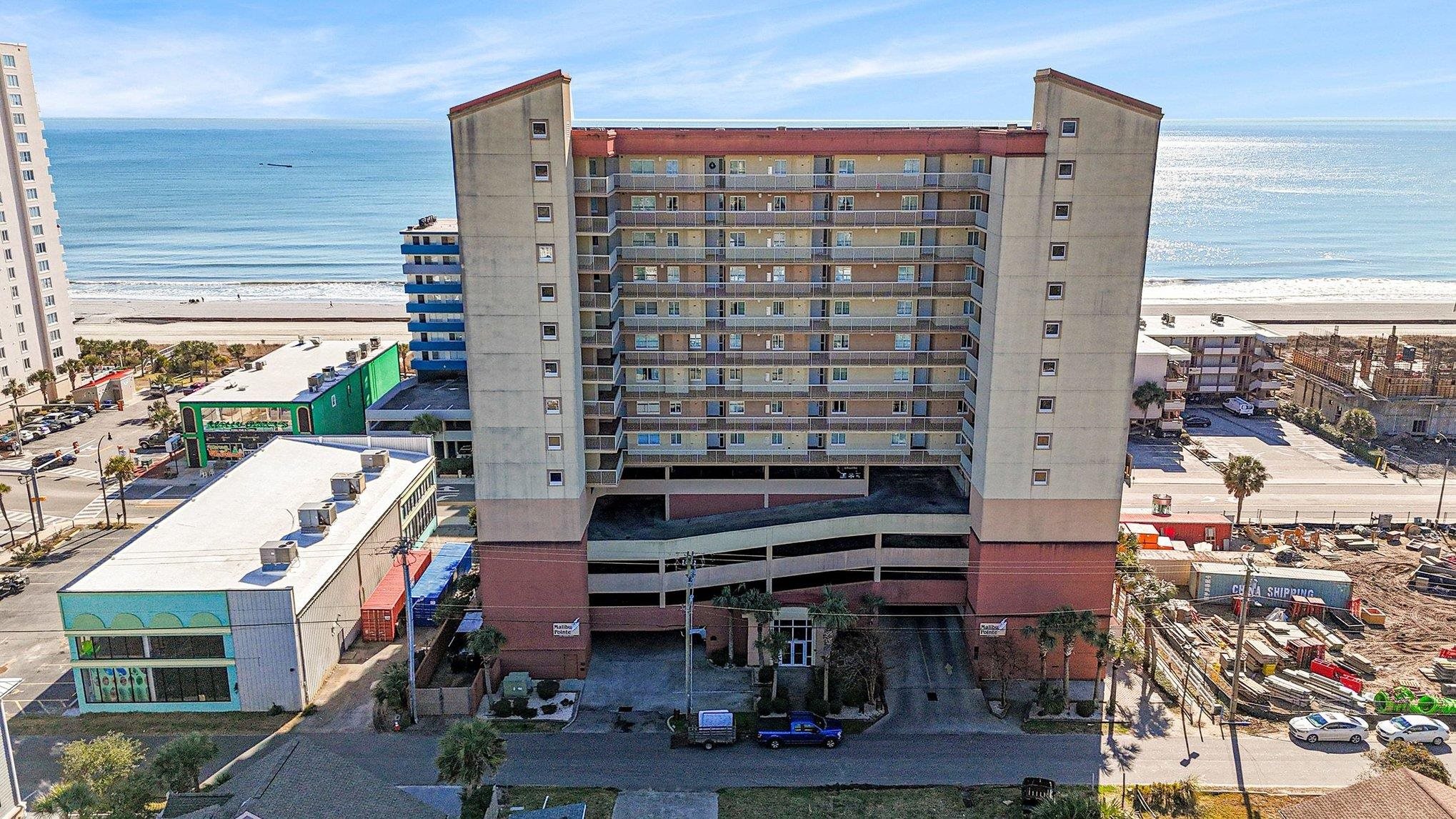 View of apartment building / complex featuring view of water and beach