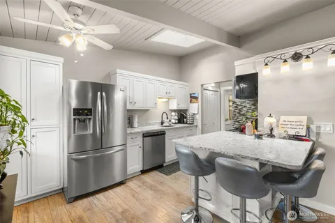 a kitchen with stainless steel appliances a dining table chairs refrigerator and microwave