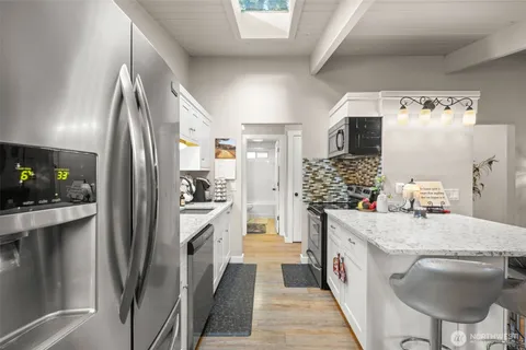 a kitchen with kitchen island a counter top space a sink stainless steel appliances and cabinets