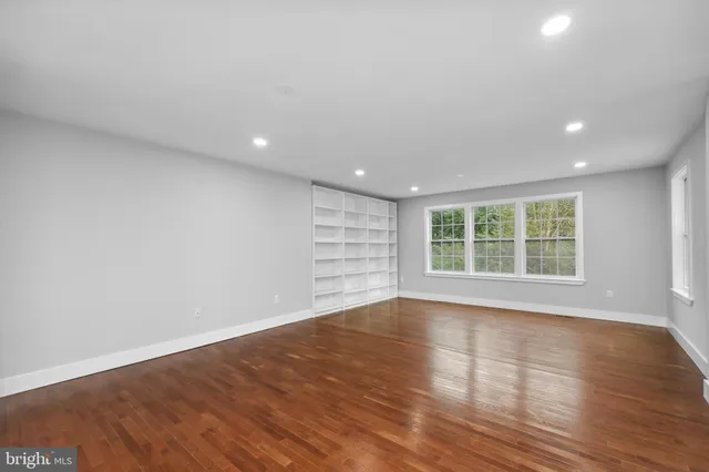 a view of an empty room with wooden floor and windows