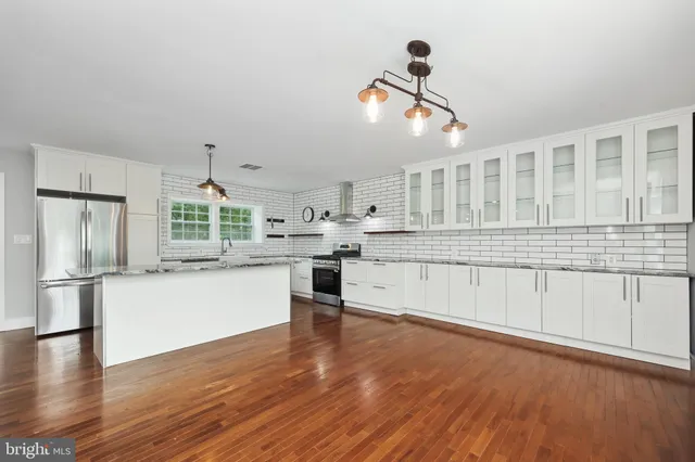 a large white kitchen with sink and refrigerator