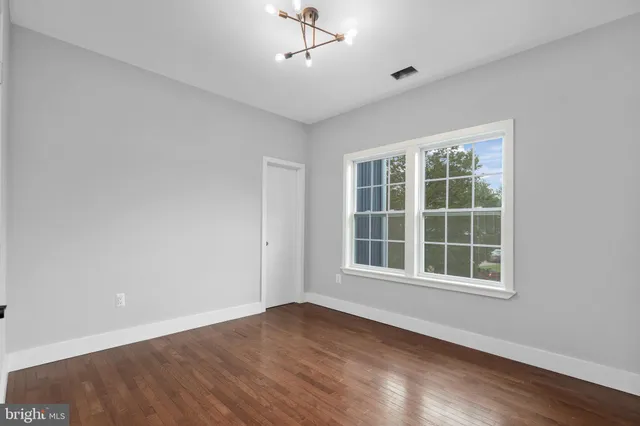 a view of empty room with wooden floor and windows