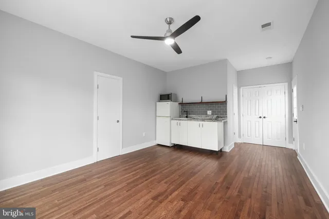 a big room with wooden floor and a ceiling fan